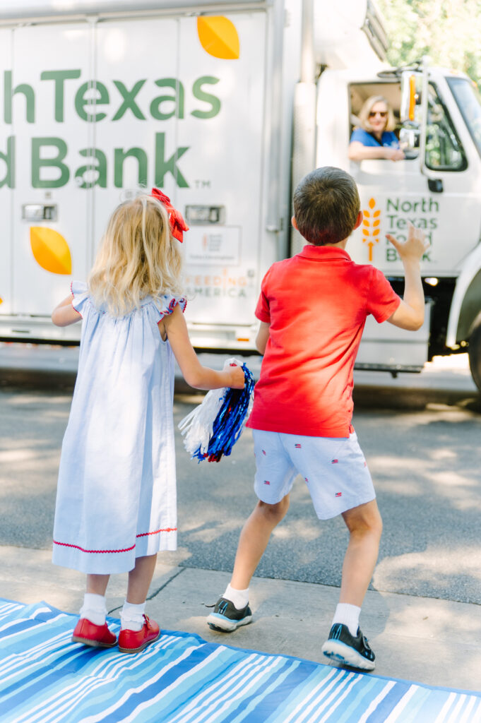 Two young siblings trying to catch candy from a North Texas Food Bank truck at the Highland Park 4th of July Parade.