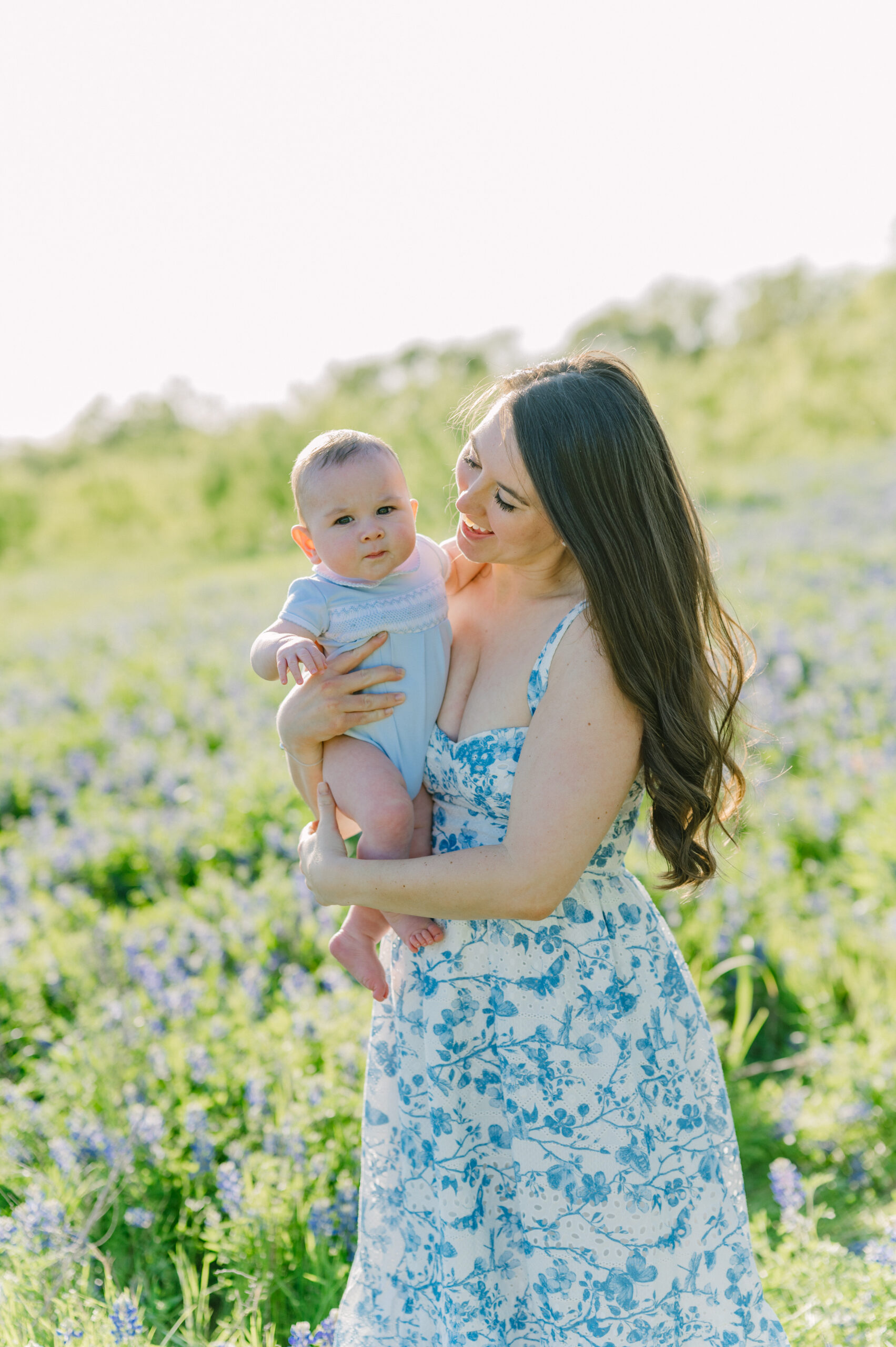 Mother dancing with her baby in a field of bluebonnets.