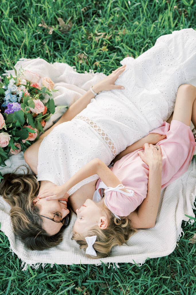 Mother and daughter on a blanket in a grassy Dallas field.